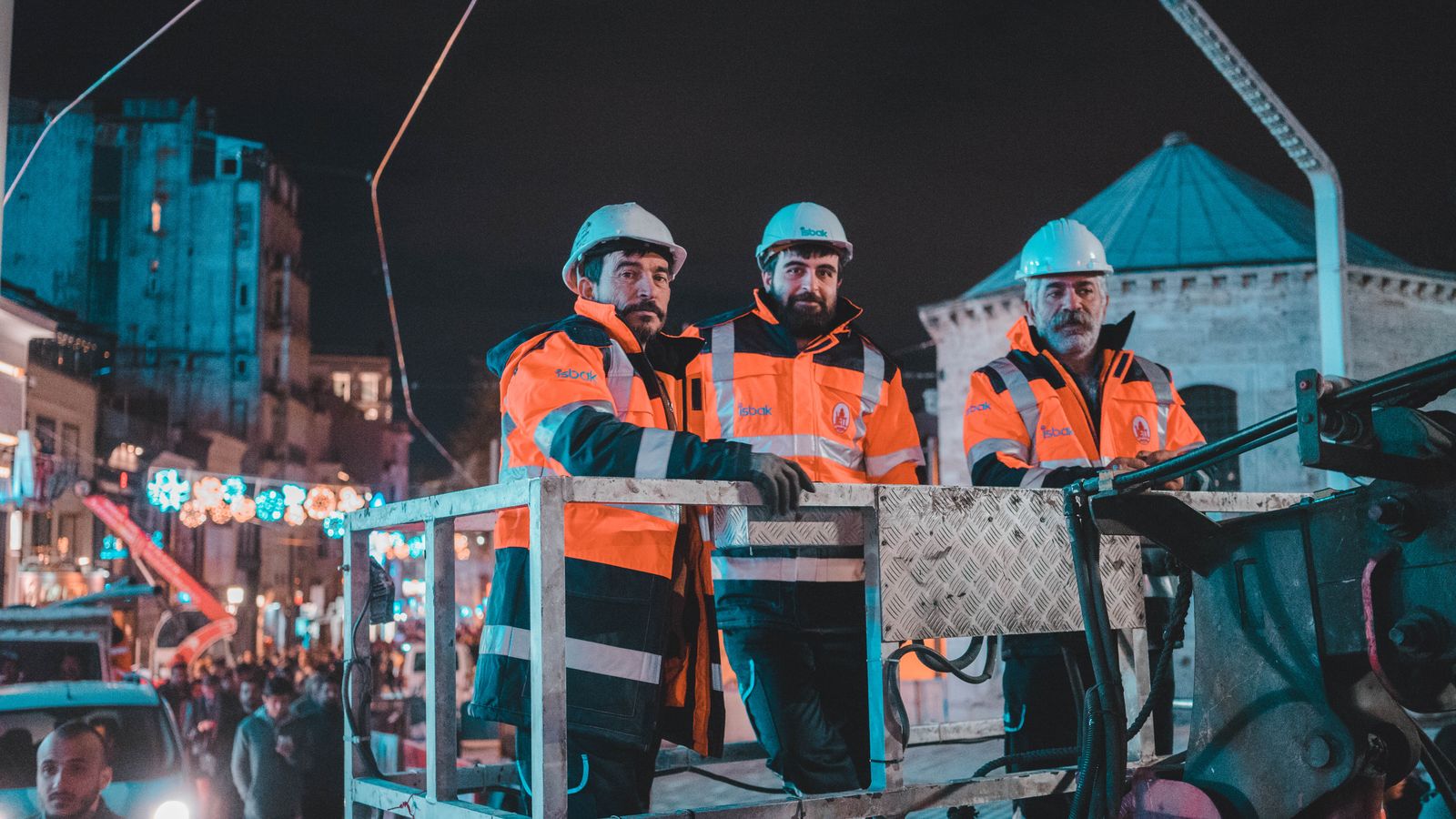 Crew in high-visibility gear working from a lift at night
